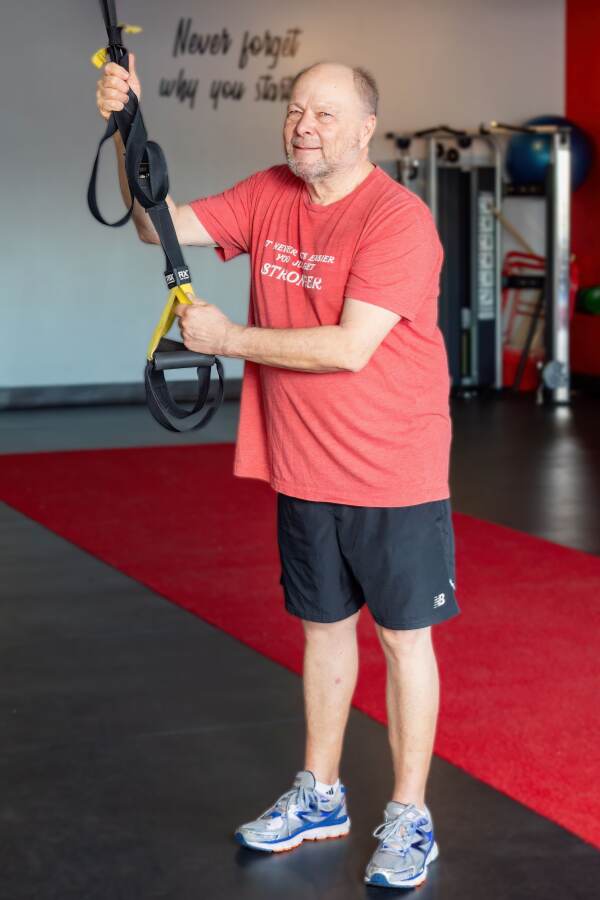 Mature male works with some fitness equipment at his personal trainers studio